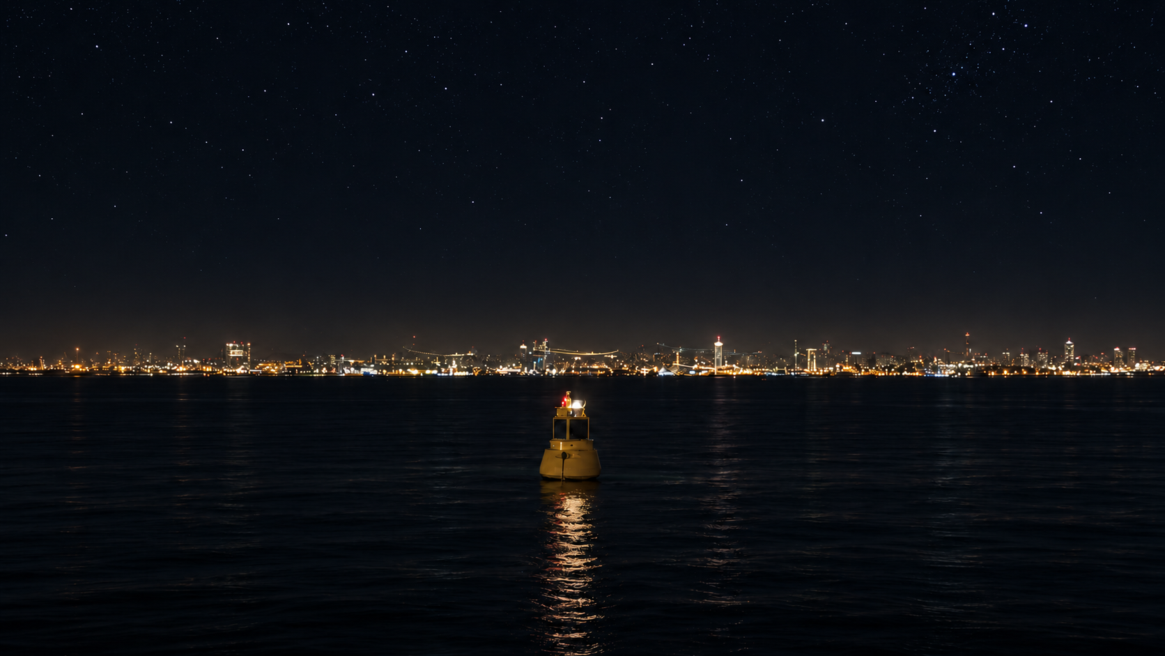 Illuminated marine buoy reflecting on calm harbor water beneath a starry sky